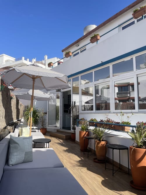 Vila Alexandra terrace with striped umbrellas, potted plants, and lounge seating overlooking Costa da Caparica