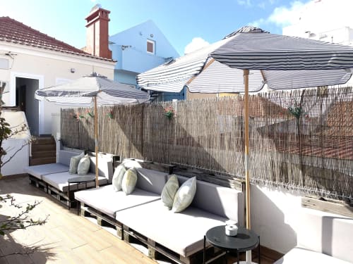 Rooftop terrace at Vila Alexandra hostel in Costa da Caparica with striped umbrellas, lounge seating, and city views