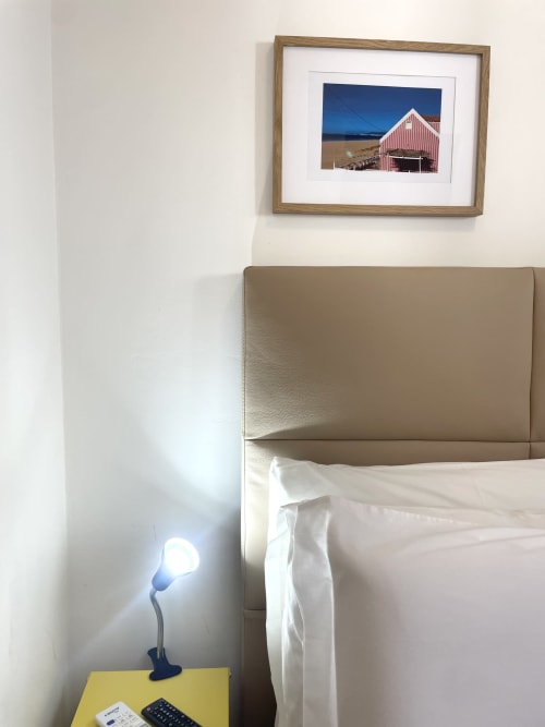 Vila Alexandra hostel room in Costa da Caparica with framed coastal artwork, beige headboard, and modern reading lamp