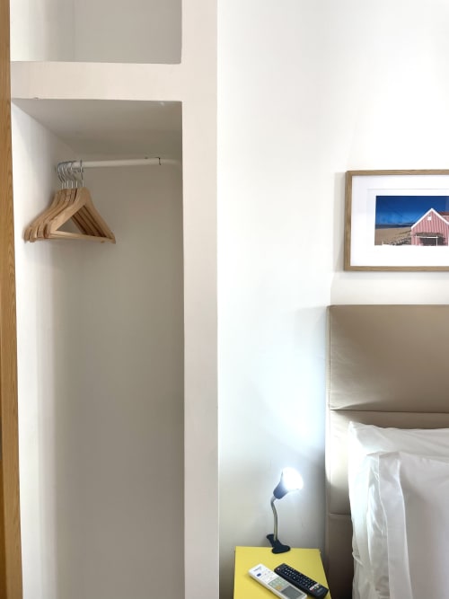 Vila Alexandra hostel room B5 in Costa da Caparica with wooden hangers, framed beach barn photo, and desk lamp
