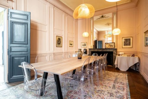 Salle à manger élégante de l'hôtel Henri II au Mans avec table en bois, chaises transparentes et cheminée