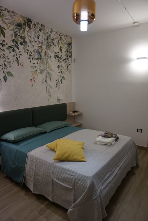 Camera da letto moderna alla Dimora Di Ipno B&B a Vallata con arte botanica alle pareti, testata verde e lampada in ottone al soffitto