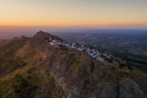Casas de Juromenha hilltop village at sunset with white buildings on rocky cliffs overlooking Portuguese countryside