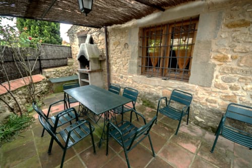 Terraza cubierta con mesa de comedor y sillas en la casa rural Can Gat Vell en Girona, Cataluña