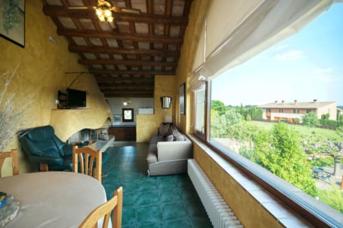 Terraza soleada con muros amarillos, suelo de baldosas verdes y vistas panorámicas del paisaje rural en Girona, Cataluña