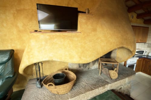 Chimenea rústica con cestas tejidas y utensilios de cocina en la casa Can Gat Vell, Girona, España