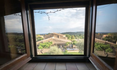 Vistas desde la ventana de la casa rural Can Gat Vell en el Empordà, con vistas a huertos en terrazas y campiña ondulante
