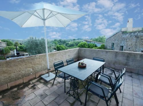 Terraza en la azotea de Can Gat Vell en Girona con mesa de comedor, sombrilla blanca y vistas a las montañas