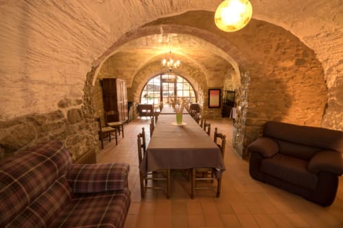 Comedor abovedado de piedra en la casa rural Can Gat Vell de Girona, con techos arqueados, muebles rústicos e iluminación cálida