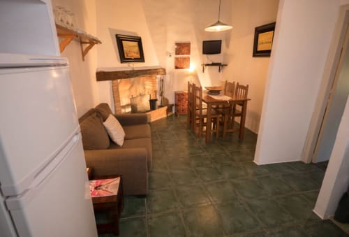 Acogedor salón con chimenea, comedor y cocina en la casita Can Gat Vell, Girona