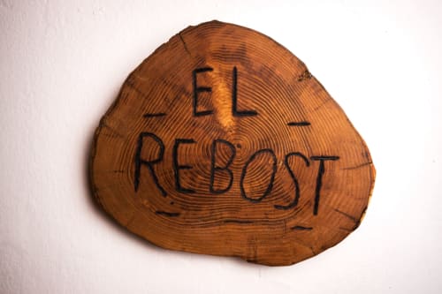 Tronco de madera con 'El Rebost' grabado en la casa rural Can Gat Vell en Girona, Empordà