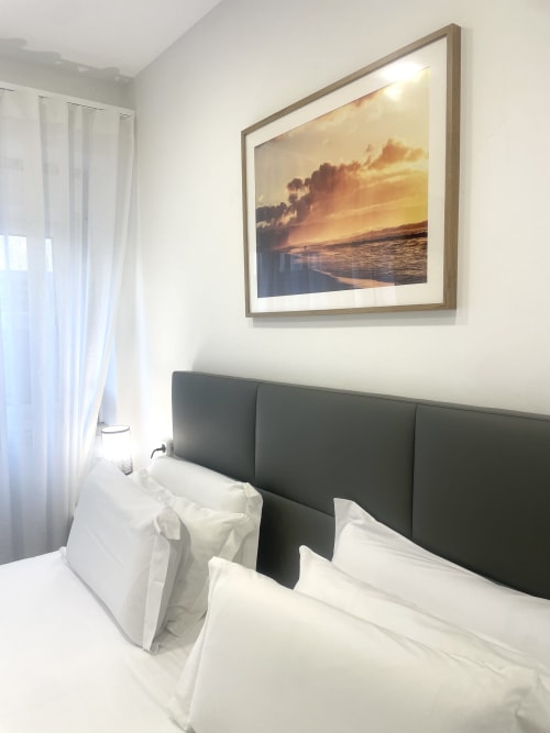Praia Morena room at Vila Alexandra hostel in Costa da Caparica with dark headboard, white bedding, and sunset beach artwork