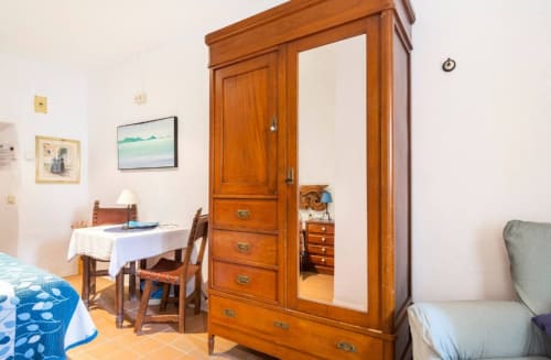 Espaciosa habitación doble en Can Gat Vell en Girona con armario de madera, mesita comedor y mobiliario confortable.