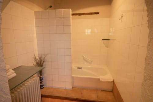 Baño moderno con azulejos blancos, bañera y ducha en la casita Can Gat Vell en Girona, Cataluña