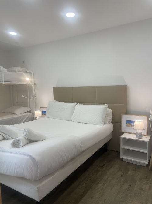 Modern hostel room at Vila Alexandra in Costa da Caparica with queen bed, nightstand lamp, and bunk beds visible
