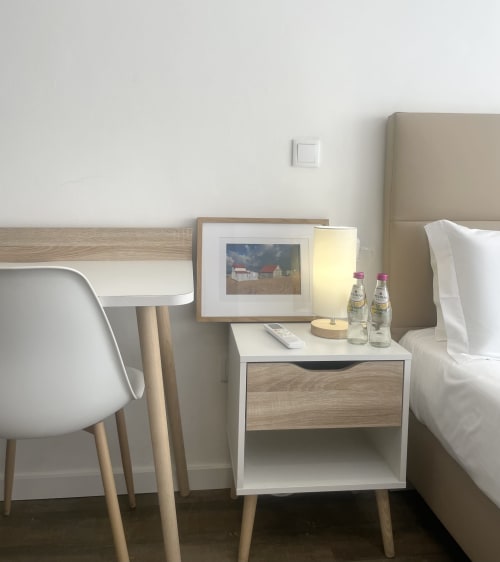 Modern hotel bedroom at Vila Alexandra in Costa da Caparica with bed, nightstand, desk, lamp and water bottles