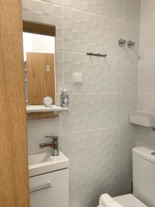 Modern bathroom in Room 8 at Vila Alexandra hostel, Costa da Caparica with white tile walls, sink, mirror and shower fixtures