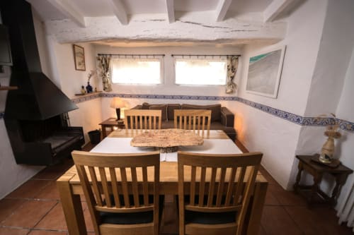 Comedor rústico en la casa rural Can Gat Vell con vigas de madera, chimenea y vistas al jardín en Girona
