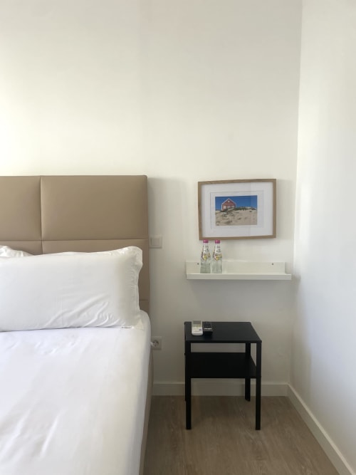 Modern bedroom at Vila Alexandra hostel in Costa da Caparica with beige headboard, white bedding, black nightstand, and