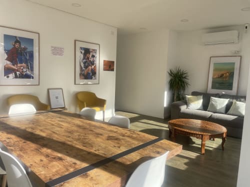 Modern common area at Vila Alexandra hostel in Costa da Caparica with wooden tables, seating, and coastal artwork