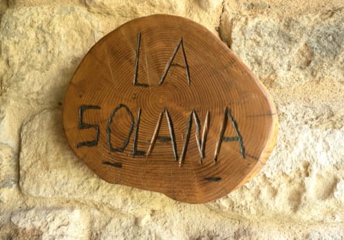Letrero circular de madera grabado con 'La Solana' en la masía Can Gat Vell en Girona, España