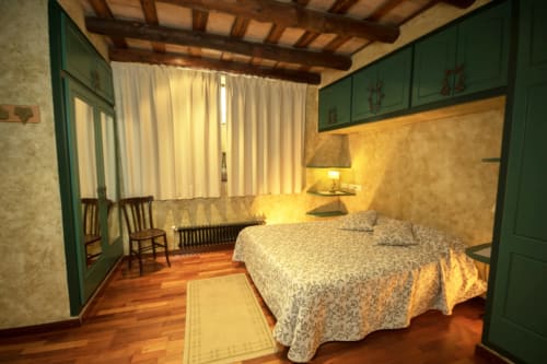 Dormitorio rústico en la casa rural Can Gat Vell, Girona, con vigas de madera, armarios verdes y camas gemelas