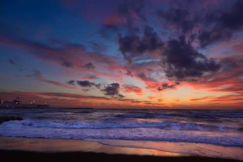 Stunning sunset over the Atlantic Ocean at Costa da Caparica beach with waves and dramatic sky near Vila Alexandra hostel