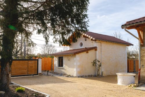 Villa contemporaine du Domaine du Haut de la Dombes avec façade en pierre de taille, portail en bois et cour de jardin