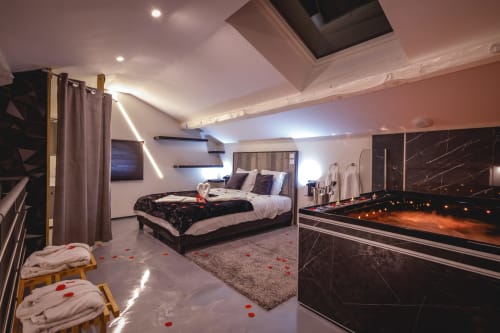 Chambre luxueuse du Domaine du haut de la Dombes avec équipements modernes, éclairage tamisé et pétales de roses romantiques.