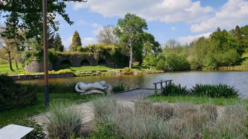 Jardin paisible au bord de l'eau de l'Hôtel Saint Roch avec sculpture en pierre, terrasse riverside et paysagisme luxuriant à Saint-Yrieix