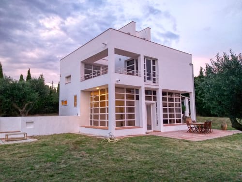 Villa blanca moderna con grandes ventanales en Finques Garcia Enrich en Palafrugell, España, con jardines cuidados y patio