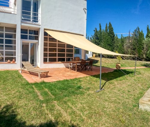 Terraza de Finques Garcia Enrich en Palafrugell con toldo crema, mobiliario de madera y jardín verde