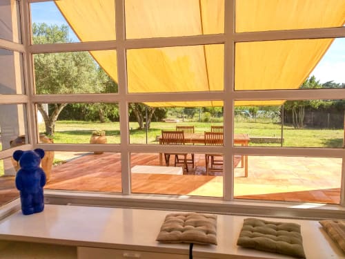 Terraza soleada del hotel Finques Garcia Enrich en Palafrugell, España con toldo amarillo, muebles de madera y exuberante vegetación