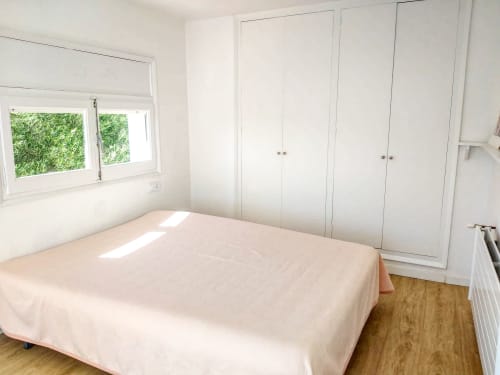 Dormitorio luminoso en Finques Garcia Enrich en Palafrugell con cama queen, armarios empotrados blancos y vistas al jardín