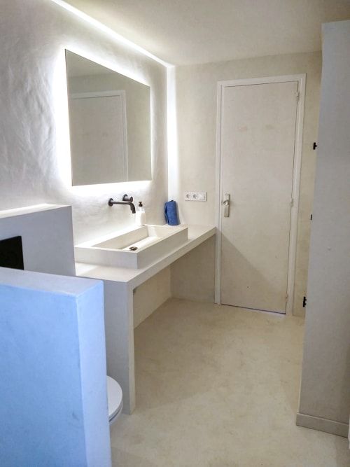 Baño moderno con espejo iluminado, tocador blanco e inodoro en Finques Garcia Enrich, Palafrugell