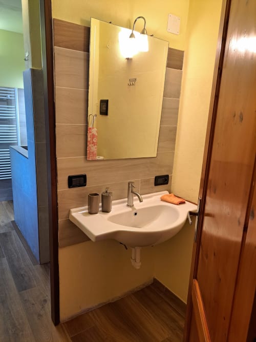 Bathroom at Corte Pincione B&B in Montecarlo with white sink, mirror, and wooden accents