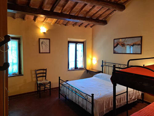 Rustic bedroom at Corte Pincione B&B in Montecarlo with exposed wooden beams, iron bed frames, and warm lighting