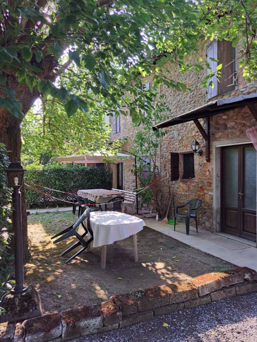 Shaded courtyard patio at Corte Pincione B&B in Montecarlo with dining tables and stone buildings