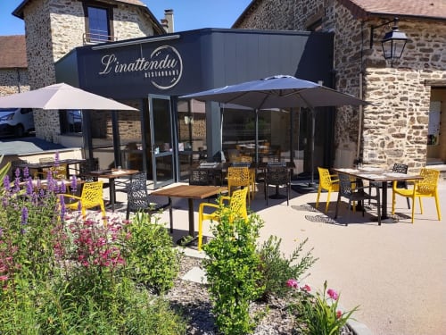 Terrasse extérieure du restaurant L'Inattendu avec chaises jaunes, parasols et plantes fleuries à l'Hôtel Saint Roch, Saint-Yrieix