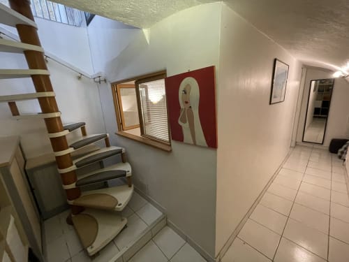 Couloir avec escaliers de l'appartement Chez Adrien Paris, au design moderne et œuvres d'art sur mur bordeaux