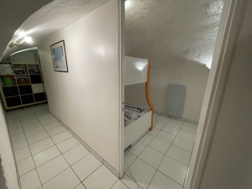 Couloir lumineux de studio chez Chez Adrien Paris avec carrelage, étagères de rangement et entrée de chambre visible