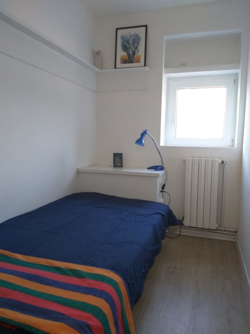 Dormitorio compacto en el hotel Finques Garcia Enrich en Palafrugell con ropa de cama azul, lámpara de escritorio y ventana con vista al radiador.