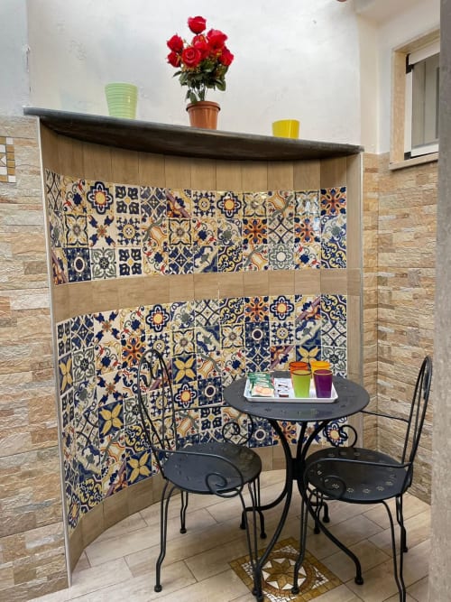 Accogliente angolo sala da pranzo presso la San Nicola Suite a Sorrento con rivestimento decorativo in maiolica, tavolo e sedie bistrot neri