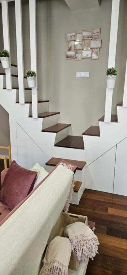 Escada moderna com corrimãos brancos e degraus em madeira escura no apartamento de Matosinhos, sofá creme abaixo