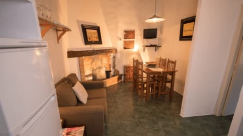 Acogedor salón en el alojamiento Can Gat Vell en Girona con chimenea, butaca y mesa para dos