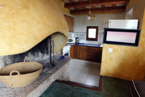 Cocina rústica en Can Gat Vell B&B en Girona con paredes amarillas, fregadero de piedra y decoración catalana tradicional