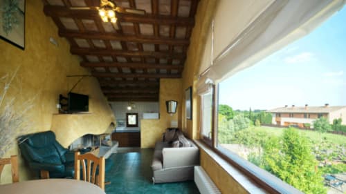 Terraza de la casa rural Can Gat Vell en Girona con paredes amarillas, vigas de madera y vistas al campo