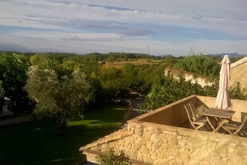 Terraza de Can Gat Vell con vistas a la campiña del Empordà con piscina de piedra, sombrilla y campos verdes en Girona