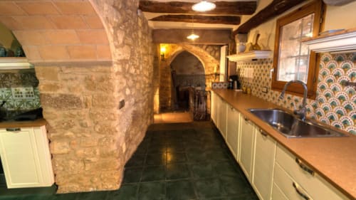 Cocina de piedra con vigas de madera y azulejos decorativos en el alojamiento Can Gat Vell en Girona, Cataluña