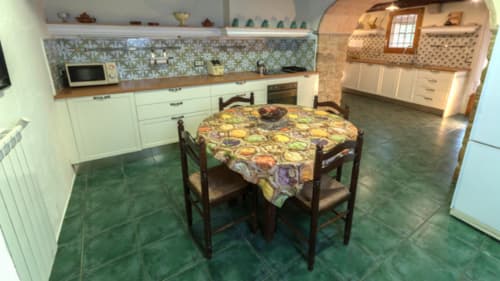 Cocina rústica y comedor en Can Gat Vell B&B en Girona, con mesa redonda y decoración tradicional española